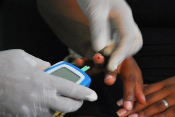 Un trabajador de la salud mide los niveles de azúcar en sangre de un paciente