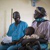阿塔尔医生与来自苏丹的一位难民妇女和她营养不良的儿子在本杰镇的医院里交谈。