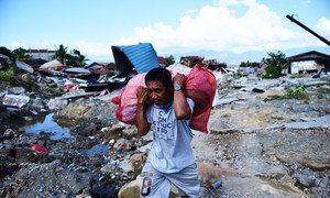 Residents carry possessions salvaged from the rubble of homes in West Palu, Central Sulawesi, after the earthquake and tsunami that struck Sulawesi on 28 September 2018.