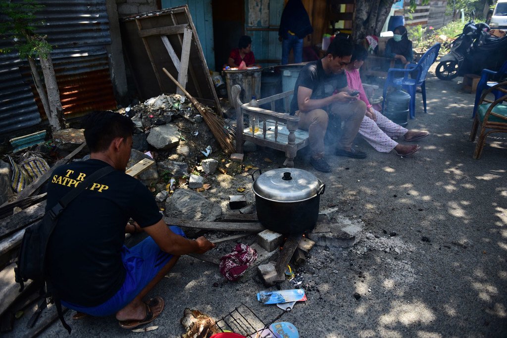 一名居民正在家门前用简单的设备做饭，因为他们仍然担心印度尼西亚苏拉威西岛中部帕卢市会发生余震。