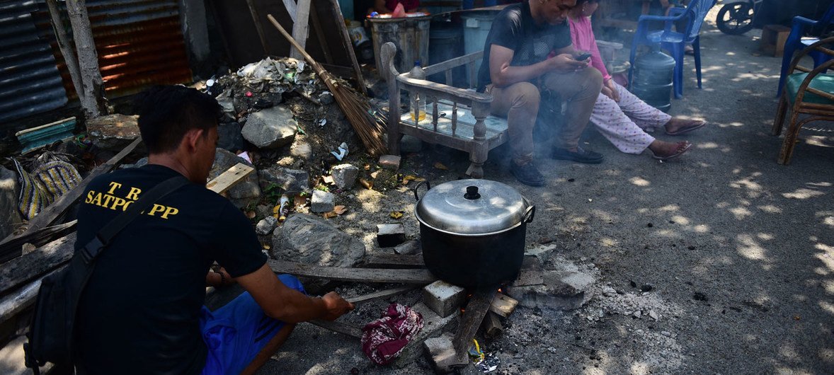 一名居民正在家门前用简单的设备做饭，因为他们仍然担心印度尼西亚苏拉威西岛中部帕卢市会发生余震。