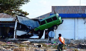 A man walks past a car hanging on the roof of a house in the aftermath of the tsunami which struck after an earthquake hit Palu, Central Sulawesi, Indonesia. (29 September 2018)