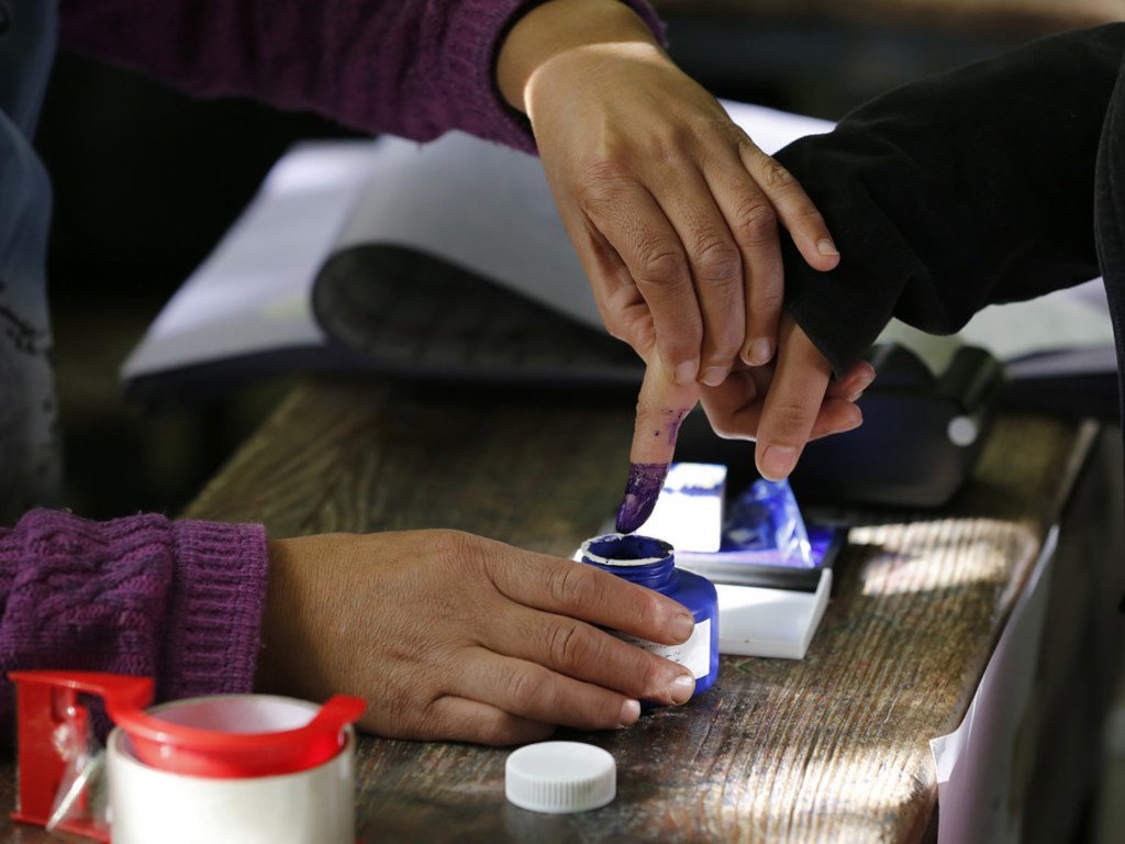 在阿富汗议会选举中，一名在喀布尔投票中心刚投了票的妇女将手指蘸入不可去除墨水中。