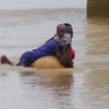 A mother and child attempt to escape the flood water in Niger State, Nigeria, following torrential rains which have hit the region since mid-July 2018. 