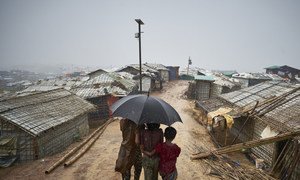 Rohingya refugees make their way down a footpath during a heavy monsoon downpour in Kutupalong refugee settlement, Cox's Bazar district. 2018.