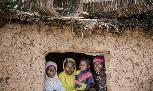 Several members of a family look from the windows of their house in the village of Dargué, Maradi region, Niger on August 16, 2018.