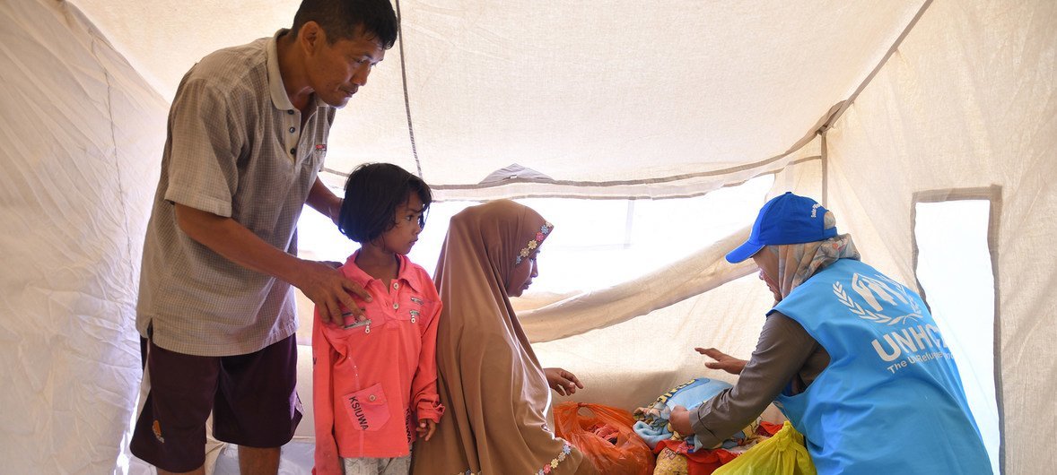 An UNHCR employee helps a family of survivors of the earthquake in Central Sulawesi move into a UNHCR emergency family tent, in the Wani Village of the Indonesian island of Sulawesi. 25 October 2018.