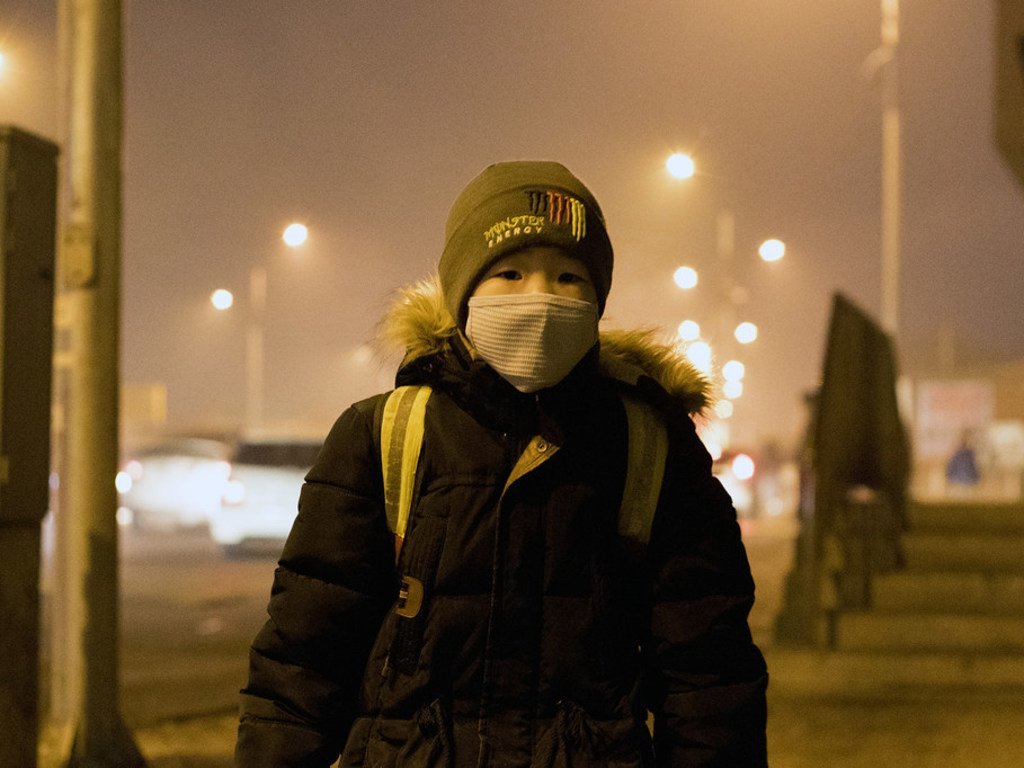 在蒙古首都乌兰巴托，一个男孩正在等待公交车去当地的一所学校，那里的空气污染水平非常危险。