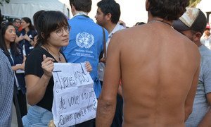 Central american migrants at the Jesús Martínez 'Palillo' stadium located in the east of Mexico City. A woman holds a poster asking: Are you afraid to return to your country? 6 October 2018.