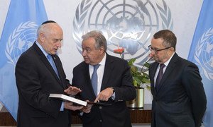UN Secretary-General António Guterres (centre) meets with Malcolm Hoenlein (left), Executive Vice Chairman and CEO of the Conference of Presidents of Major American Jewish Organizations, who presents him with a book on the Kristallnacht Nazi pogrom.