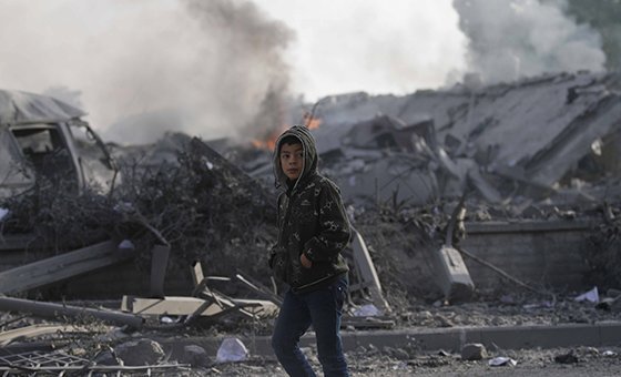 ग़ाज़ा पट्टी के दक्षिणी शहर रफ़ाह में इसराइली हवाई हमलों में तबाह हुए घरों के पास से गुज़रते हुए एक 12 वर्षीय लड़का. (नवंबर 2018)