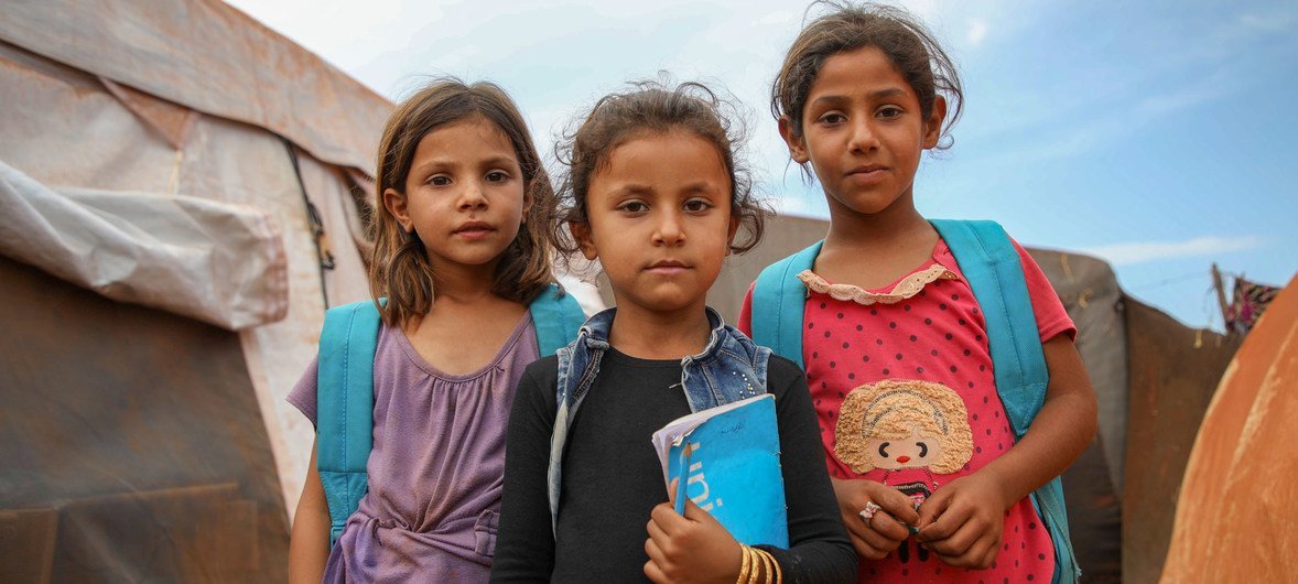  فتيات سوريات يرتدين حقائب ظهر بشعار اليونسف خارج مدرسة مشيدة من الخيام، في مخيم جونايا المؤقت في ريف إدلب الشمالي، حيث يتعلم 350 طفلا من سن 7 إلى 14 عاما.