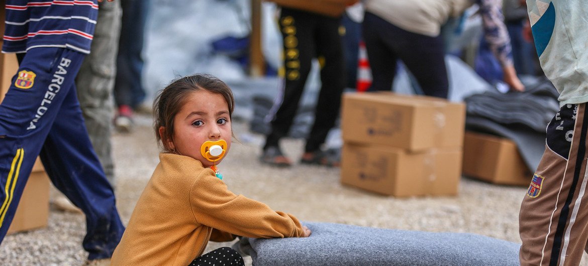 طفلة تجلس بجانب الإعانات التي تم استلامها للوقاية من البرد القارس في الشتاء داخل مخيمات دهوك.