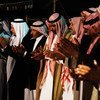 مجموعة من الرجال يرتدون الزي الأردني التقليدي، بما في ذلك الكوفية والثوب، يغنون ويصفقون أثناء عرض فني.