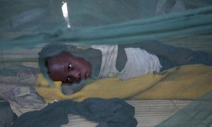 Ten-year-old girl sleeps under a mosquito net with many holes, near Maganja da Costa, Mozambique. She has malaria, and is born with a club foot.
