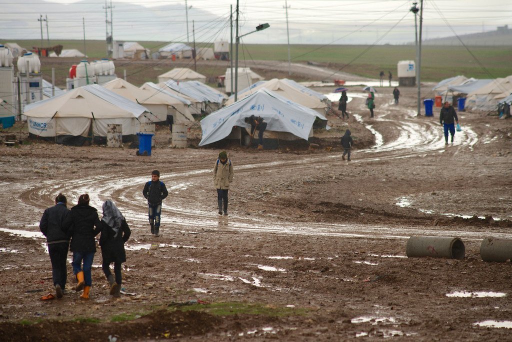 In this file photograph, children at a refugee camp in Suleimaniyah, northern Iraq, walk to their school, along a muddy path on a cold, rainy winter day.