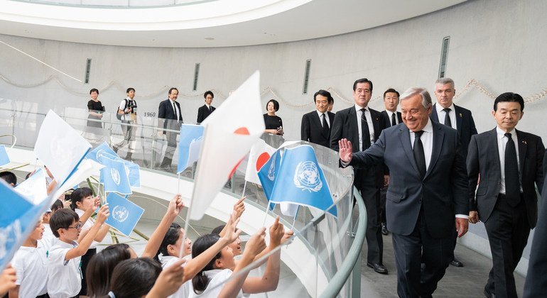 Crianças de escolas japonesas acenam com bandeiras japonesas e das Nações Unidas para receber o secretário-geral António Guterres no Museu da Bomba Atómica de Nagasaki.