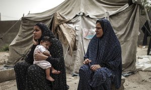 两名妇女和一名儿童坐在她们位于加沙地带的临时住所前。 除住房条件恶劣外，加沙儿童的食品和健康等基本需求也难以得到满足。