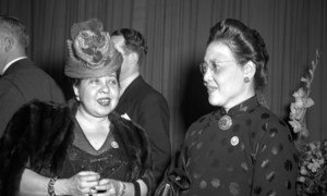 Minerva Bernardino e Bertha Lutz conversam em um evento formal, defendendo os direitos das mulheres e sua inclusão na Carta das Nações Unidas .