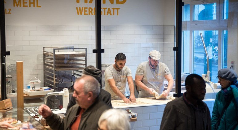 Master baker Björn Wiese (wearing cap) teaches Mohamad Hamza Alemam how to bake.