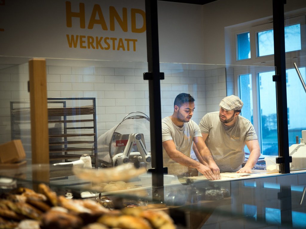 Le réfugié syrien Mohamad Hamza Alemam (à gauche) est formé par le maître boulanger Björn Wiese (casquette), à la boulangerie Backwerkstatt d'Eberswalde, en Allemagne (4 décembre 2018)..