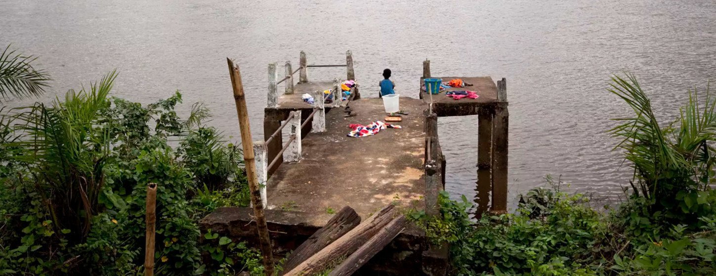 Un enfant au Libéria est assis sur une jetée.