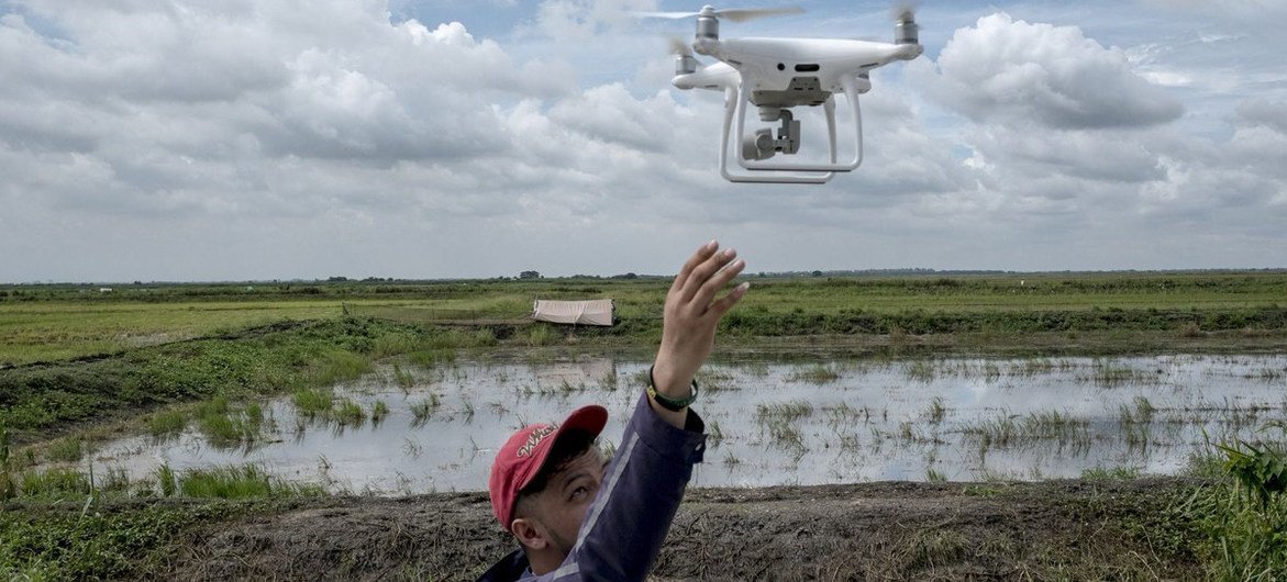A person launches a drone in a field in the Philippines. Information from drones can be used to develop reports on the extent and health of vegetation and, in the event of natural disasters, damage. 