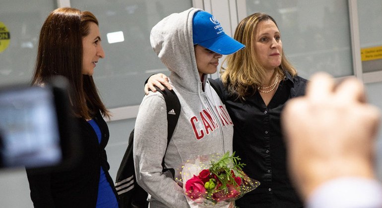 18-year-old Saudi woman Rahaf Mohammed al-Qunun (Centre) arrives at Pearson International Airport in Toronto and is welcomed by the Canadian Minister for Foreign Affairs Chrystia Freeland (right) and COSTI staff member Saba Abbas (left). Rahaf walked out of the gates wearing a Canada pullover and UNHCR cap.