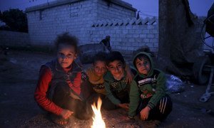 Children at Batbu camp in western rural Aleppo, Syria, burn pieces of cartons and paper to warm up at night. November 2018.