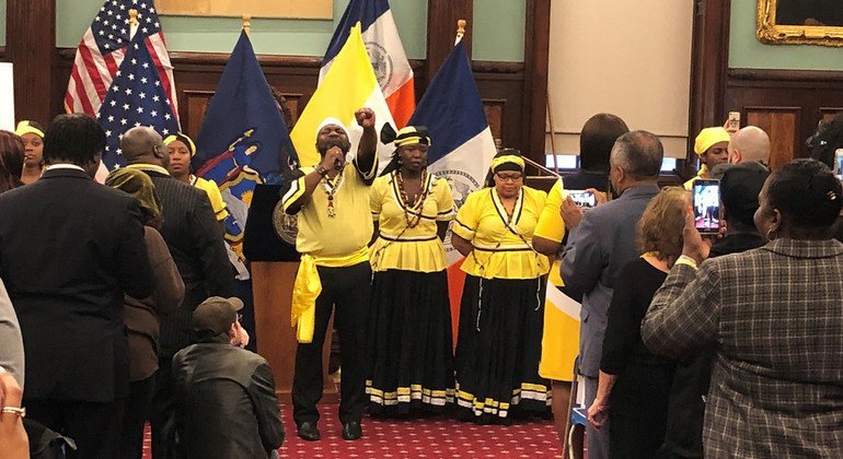 A member of the Chief Joseph Chatoyer Dance Company, customed in the Garifuna traditional colors of yellow, black and white, sings the national anthem at an event celebrating Garifuna heritage at New York’s City Hall.  2018.