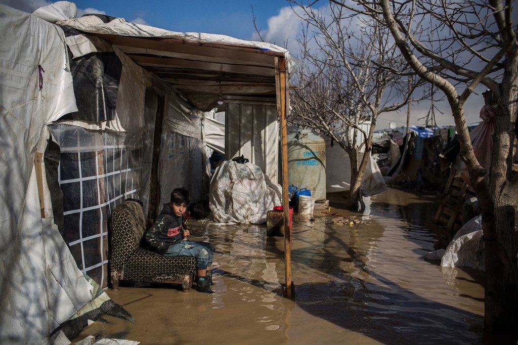 Un réfugié syrien de 9 ans originaire de Deir el-Zor est assis devant sa tente inondée au camp de peuplement informel de Dalhamiya au Liban. 9 janvier 2019.