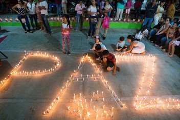 Women and children from the Mocoa community in Colombia light candles forming the word peace.
