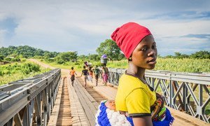 Au Malawi, une femme et son nourrisson traverse un pont pour se rendre au centre de santé Lugola à Chikulo. le pont a été construit grâce à un financement du Programme alimentaire mondial des Nations Unies (PAM)