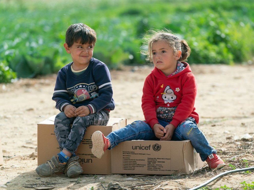 همام (5 سنوات) وأخته شام (4 سنوات)، وهم من عائلة سورية لجأت إلى الأردن قبل ست سنوات، يجلسون على علب تحتوي ملابس شتوية للأطفال.