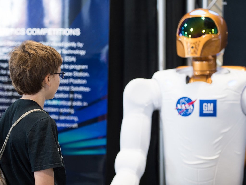 زائر في مهرجان العلوم والهندسة بالولايات المتحدة الأمريكية  يتأمل أحد روبوتات وكالة ناسا الفضائية  شديدة التطور وهي بأقدام تساعدها على الحركة. 