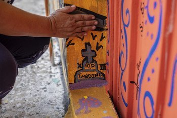 Una madre señala la tumba que pintó en un mural para expresar su dolor por el asesinato de su hijo de 17 años por una pandilla en El Salvador.
