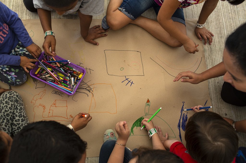 Niños centroamericanos esperan a que se tramiten sus visas humanitarias mientras dibujan en un centro de UNICEF en la frontera entre Mexico y Guatemala