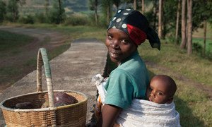 A 27-year-old Rwandan woman carries her 9-month-old baby on her back as she heads to the local market to sell avocados.