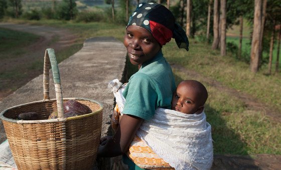 A 27-year-old Rwandan woman carries her 9-month-old baby on her back as she heads to the local market to sell avocados.