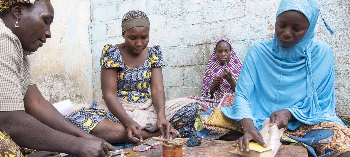 Internally displaced Cameroonian, Aminatou Sali (r), was trained by a non-Government organization to make leather goods.