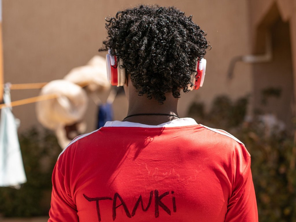 Mebratu, un joven de Eritrea de 16 años, escucha con audífonos su música favorita.