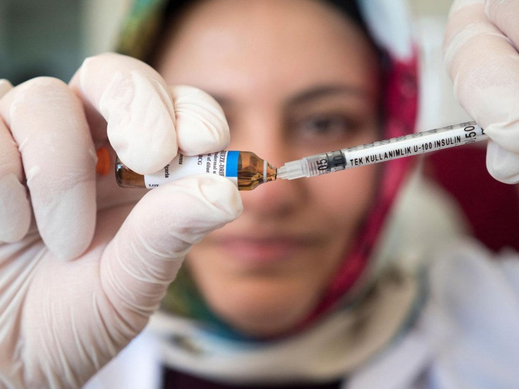 一名护士正用针筒抽取疫苗。