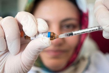 一名护士正用针筒抽取疫苗。