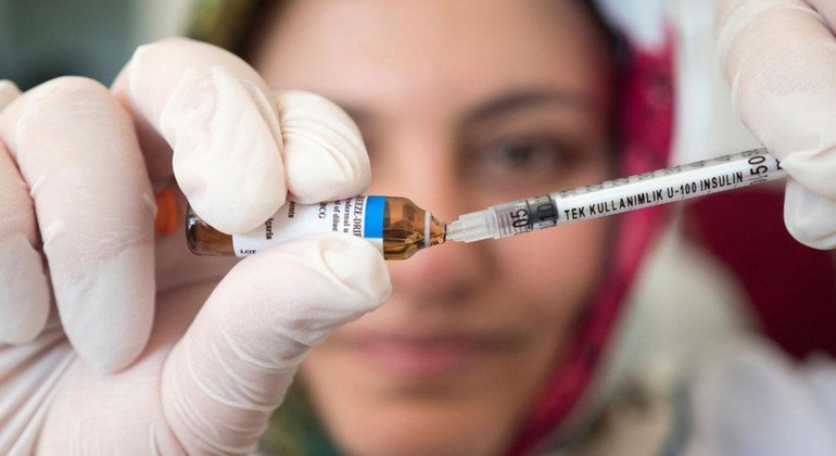 Nurse loads vaccine into a syringe.