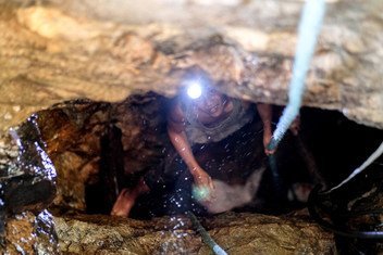 菲律宾北甘马粦省一名手工采金者从山中的矿井中往外爬。