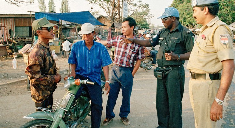 UN Police Officers serving with the UN Transitional Authority in Cambodia (UNTAC) direct traffic in the capital, Phnom Penh, in January 1993. To the far right is a police officer from India; second from right is a police officer from Ghana.