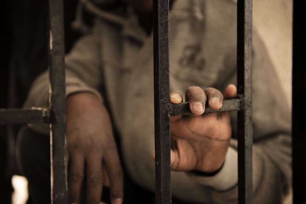 Issaa, un migrant du Niger âgé de quatorze ans, pose sa main sur un barreau d'un centre de détention, en Libye. Sa mère est décédée lorsqu'il avait 12 ans au Niger. Il a réussi à économiser 450 dollars pour effectuer la traversée vers l'Italie. Il a été a