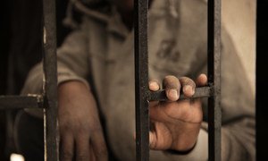 A migrant from Niger rests his hand on a gate inside a detention centre, in Libya, in 2017. He was arrested and detained before he was able to board a boat that was crossing to Italy. 