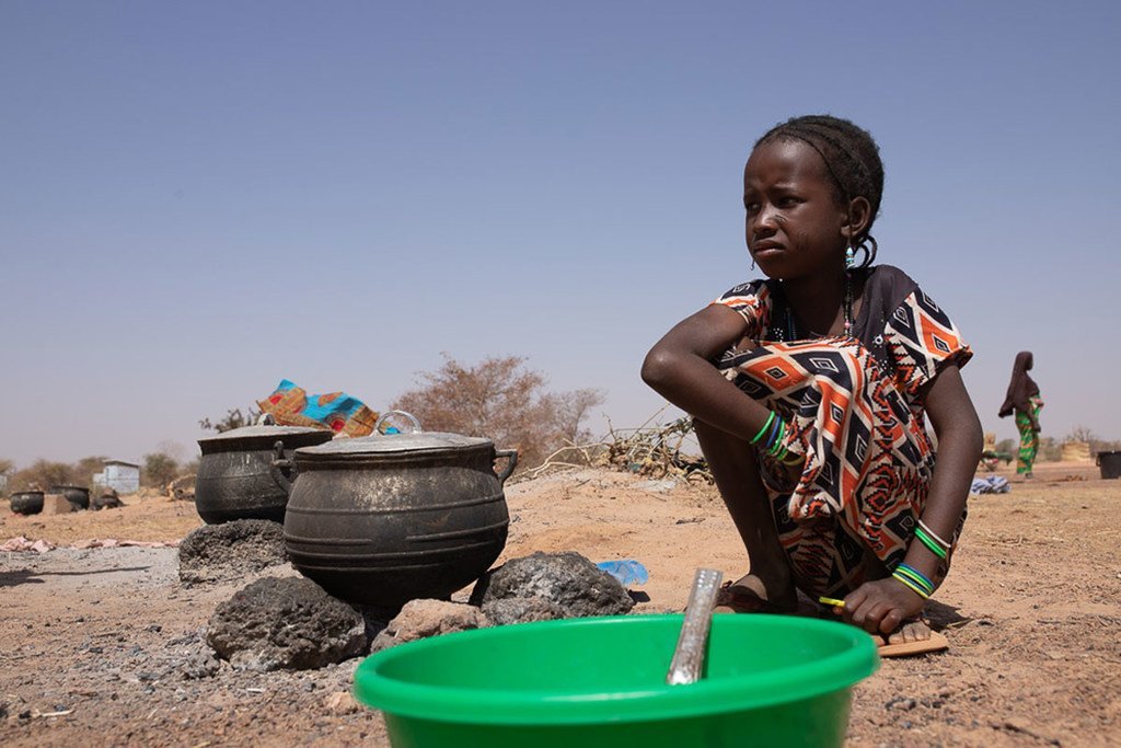 Une jeune fille devant une marmite dans un camp pour personnes déplacées à Barsalogho, dans la région du Centre-Nord, du Burkina Faso. Plus de 100.000 personnes ont été déracinées de leurs foyers en raison d'affrontements intercommunautaires.