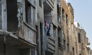 A woman stands on her balcony in the El Khalideh neighbourhood of the Old City of Homs, in Syria. (March 2019)